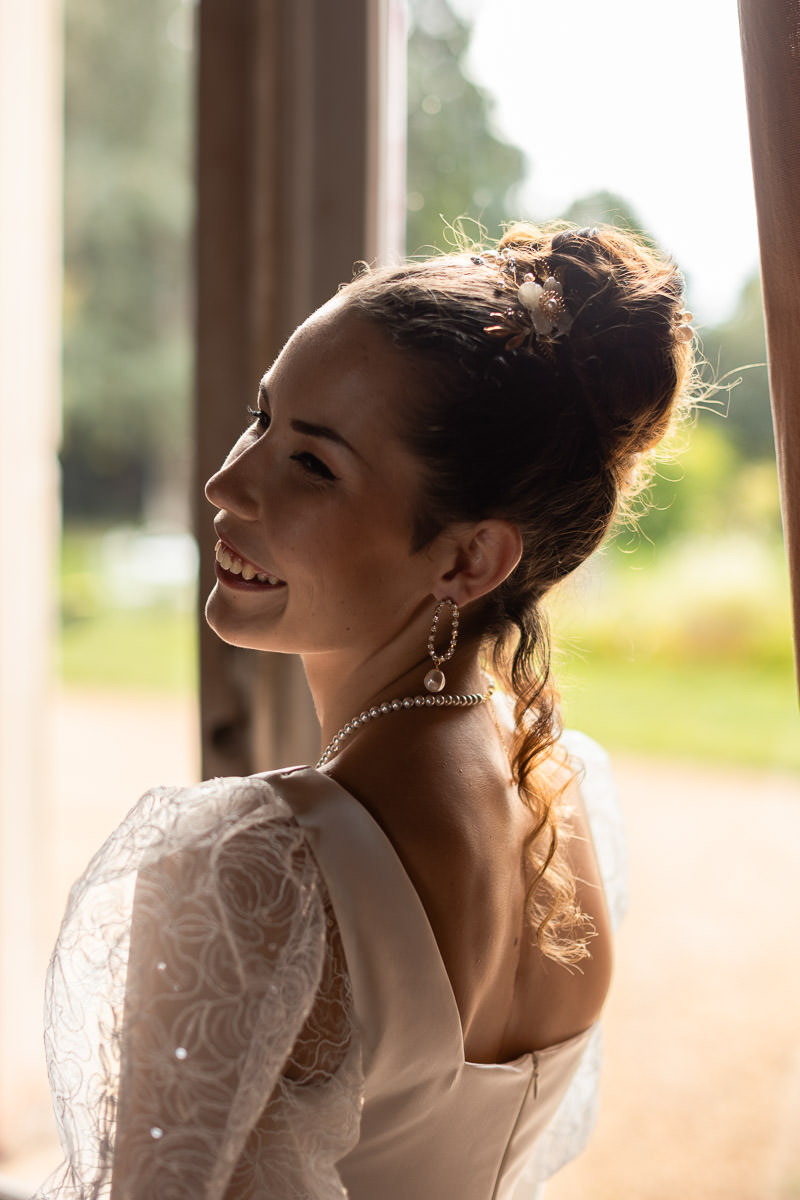 mariée style glamour Bridgerton riant à la fenêtre d'un château